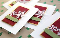 four cards with snowflakes on them sitting on top of a christmas table cloth