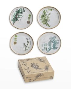 four plates sitting on top of a box next to each other with plants painted on them