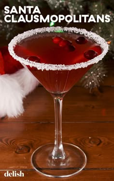 a close up of a drink in a glass on a table with christmas decorations behind it