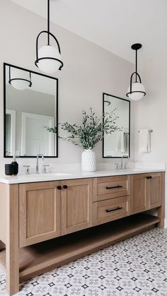 a bathroom with two sinks and mirrors on the wall, one has a vase with flowers in it