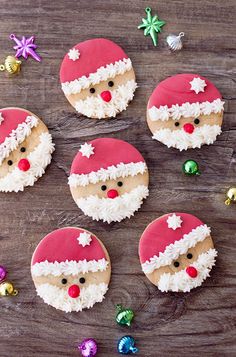 decorated cookies with frosting and santa's face are on a wooden table, ready to be eaten