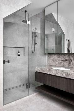 a modern bathroom with marble counter tops and gray walls, along with a walk in shower