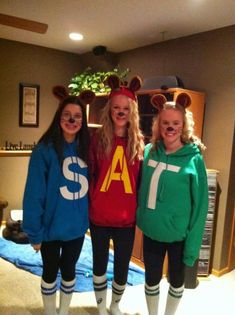 three girls dressed up in mickey mouse ears and sweaters, posing for the camera