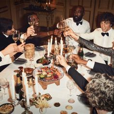 a group of people sitting around a dinner table with wine glasses in their hands and food on the plate