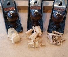 three old fashioned door knobs with wood shavings next to them on a counter