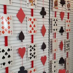 several playing cards are hanging on the wall with red and black hearts attached to them