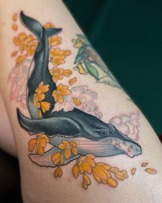 a woman's arm with a whale and flowers on it