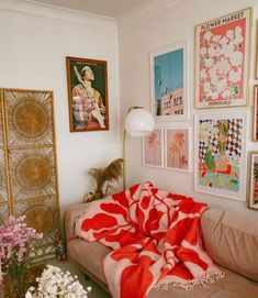 a living room filled with lots of pictures and flowers on the wall next to a couch