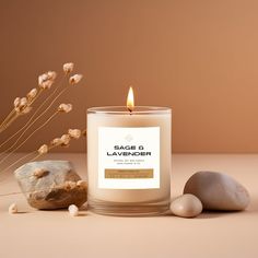 a candle sitting on top of a table next to some rocks and dried flowers in front of it