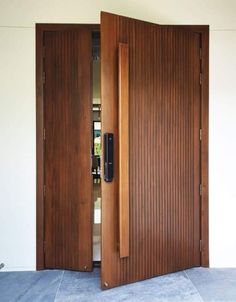 an open wooden door on the side of a white wall with blue tile flooring