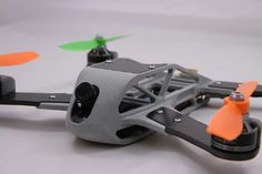 an orange and black remote control helicopter on a white surface with two propeller blades in the foreground