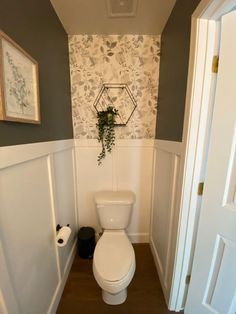 a white toilet sitting inside of a bathroom next to a doorway with pictures on the wall