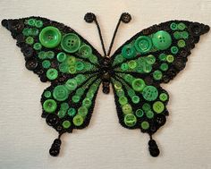 a green butterfly made out of buttons on a white surface with black trimmings