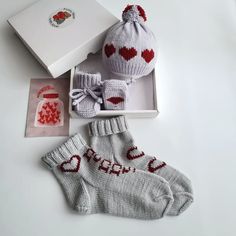 a knitted hat, mittens and booties are sitting in a gift box