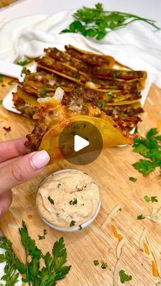 a person is dipping some food into a small bowl on a cutting board with parsley