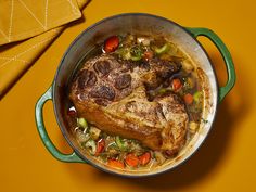 a pot filled with meat and vegetables on top of a yellow table