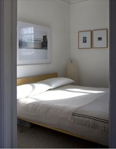 a bed sitting in a bedroom next to two framed pictures on the wall above it