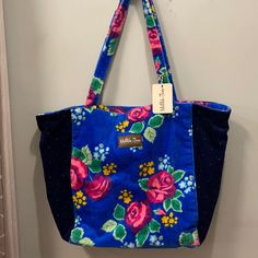 a blue floral bag hanging on the wall with a tag attached to it's handle