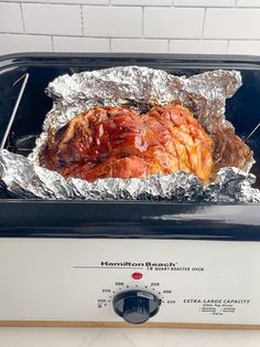 a piece of meat is on top of tin foil in a toaster oven with tongs