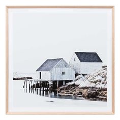 a white house sitting on top of a beach next to a body of water with rocks in front of it