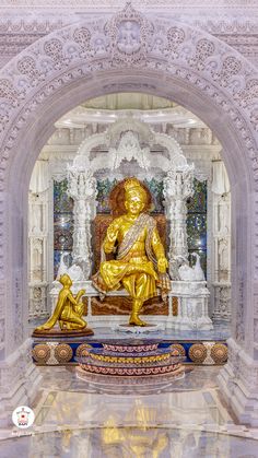 a golden buddha statue sitting in the middle of a room with white and gold walls