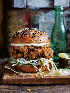 a chicken sandwich is on a wooden cutting board