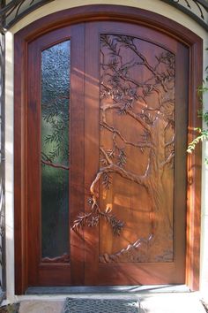 a wooden door with glass panels and a tree on the side walk in front of it