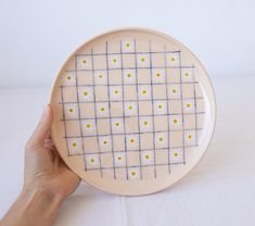 a hand holding a plate with yellow dots on it