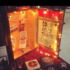 an open box with various items inside on a red cloth covered tablecloth and lighted lights