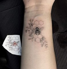 a woman's arm with a bee and flowers tattoo on the left side of her wrist