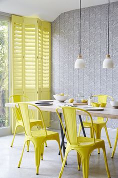 a dining room with yellow chairs and white table