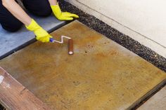 a person in yellow gloves and rubber gloves painting a concrete floor