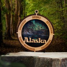 a wooden sign with the name alaska on it in front of some trees and bushes