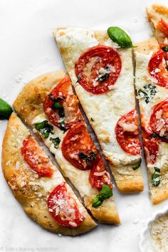 several slices of pizza on a plate with basil and tomato toppings, ready to be eaten