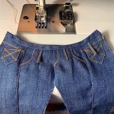 a pair of jeans that have been sewn together with sewing machine in the background