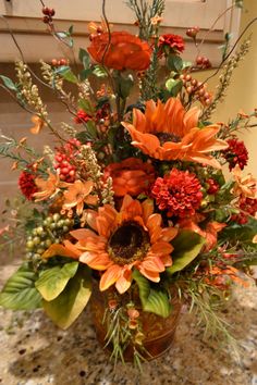 a vase filled with lots of orange flowers on top of a marble countertop next to a door