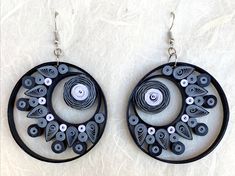 two circular earrings with black and white buttons on them