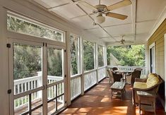 a porch with chairs, table and ceiling fan