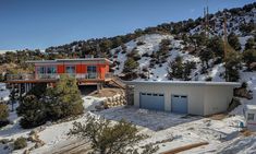 an aerial view of a house in the mountains with snow on the ground and trees around it