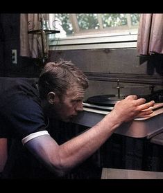 black and white photograph of man playing with record player