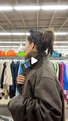 a woman standing in front of a rack of clothes