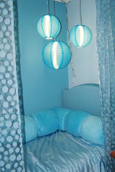 three blue lanterns hanging from the ceiling above a bed in a child's room