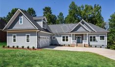 a large gray house sitting on top of a lush green field