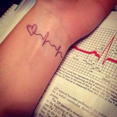 a person with a heartbeat tattoo on their arm next to an open book and a stethoscope