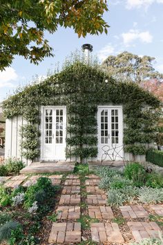 a house covered in vines and ivys with two doors on each side, surrounded by greenery