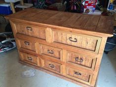 an old wooden dresser with many drawers and knobs on the bottom, sitting in a cluttered room