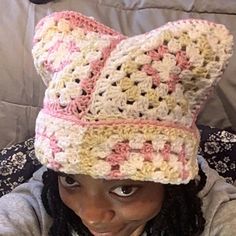 a woman wearing a crocheted bear hat while sitting on top of a couch