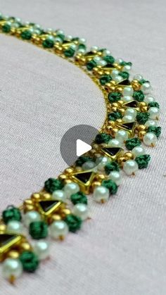 a green and white beaded necklace with gold trimmings on the bottom, surrounded by pearls