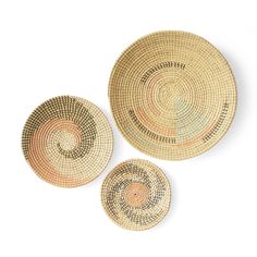 three woven baskets sitting next to each other on a white surface with an orange and black design