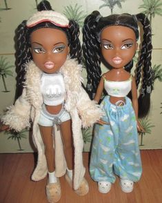 two dolls standing next to each other on a wooden floor